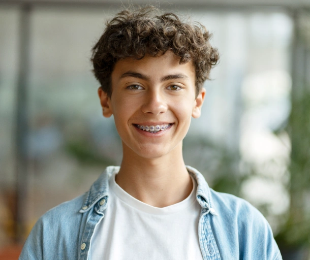 Young man smiling at camera wearing casual blue shirt in modern dental office setting.