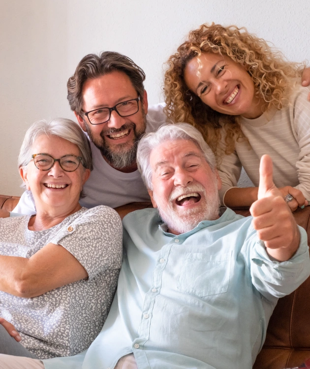 Four happy family members smiling together indoors, showing dental health and happiness.
