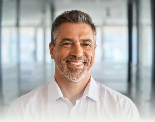 Professional headshot of smiling man in white shirt in modern office setting for River Rock Dental Austin
